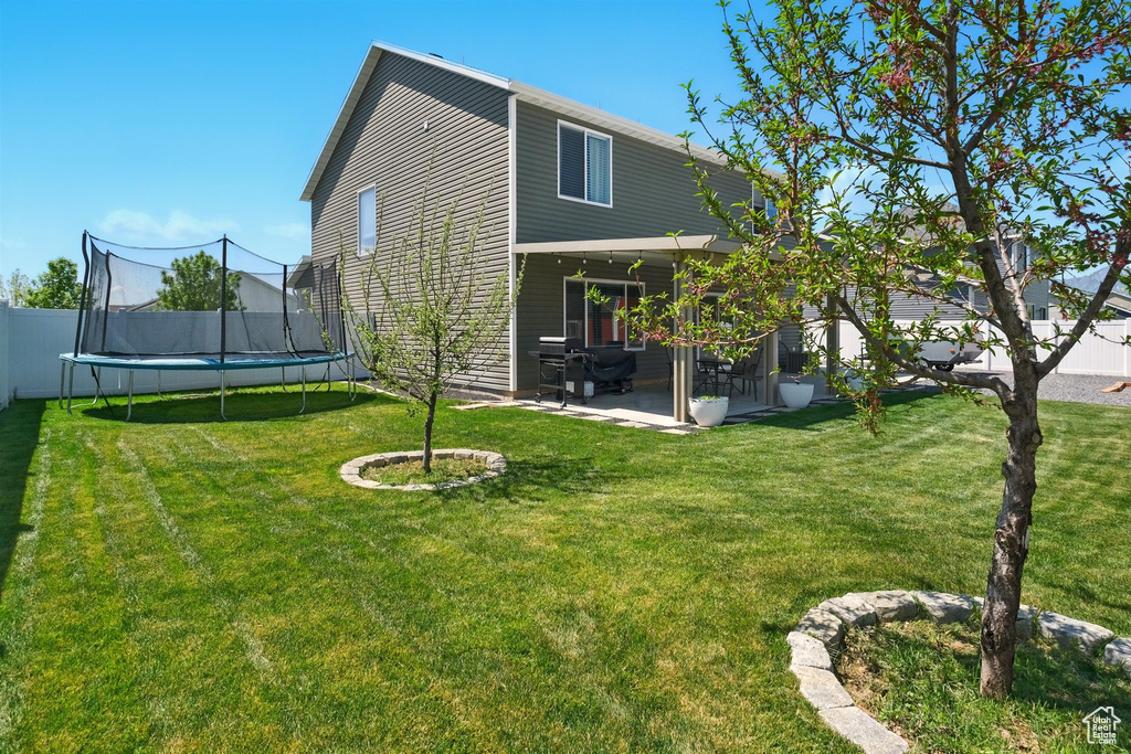 Back of property with a trampoline and a patio area