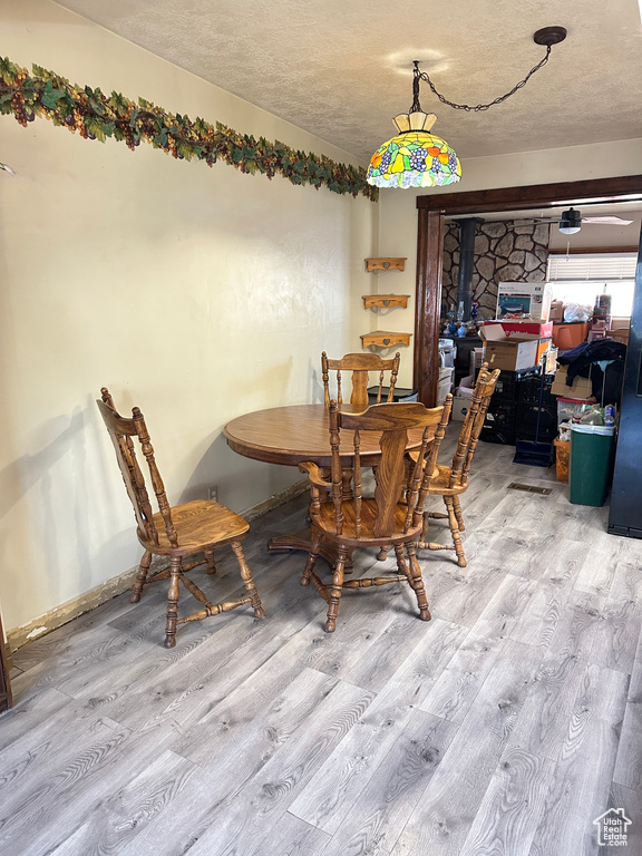 Dining space with wood finished floors, a textured ceiling, and a wood stove