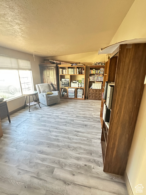Sitting room with light wood-style flooring, baseboards, and a textured ceiling