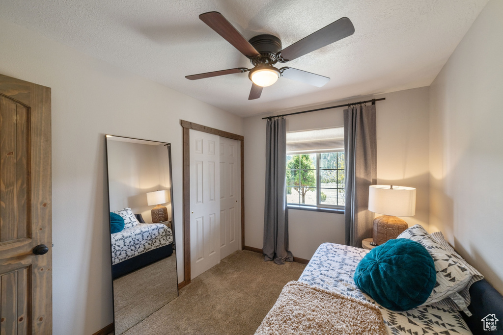 Carpeted bedroom with a ceiling fan, a closet, and a textured ceiling