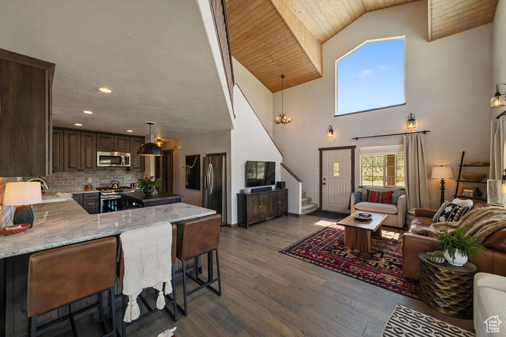 Living room featuring stairway, dark wood-type flooring, high vaulted ceiling, and recessed lighting