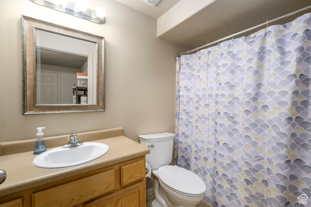 Full bathroom with a textured ceiling, toilet, vanity, and a shower with curtain