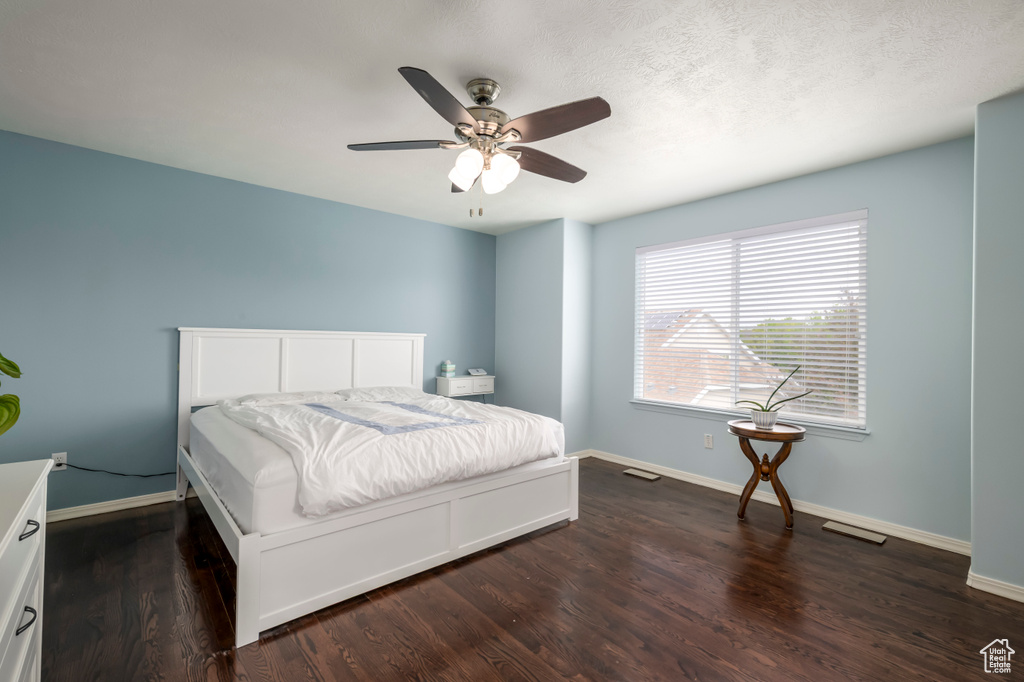 Bedroom with dark wood finished floors, baseboards, and a ceiling fan