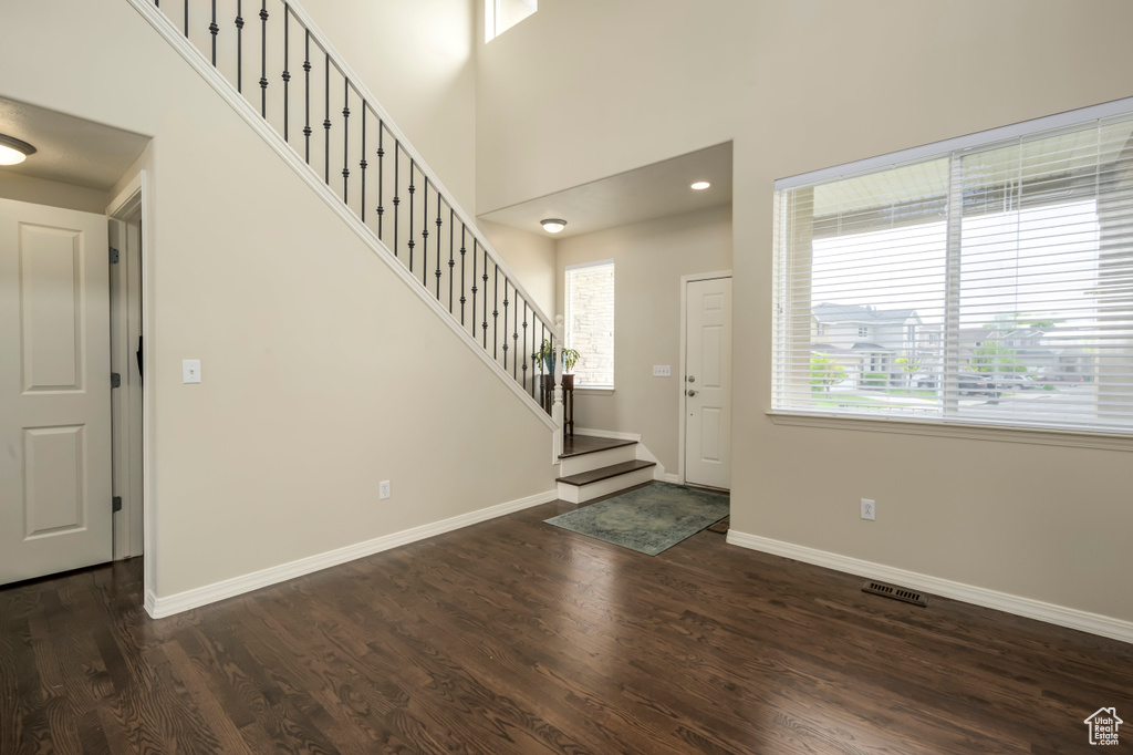 Entryway with stairs, dark wood-style flooring, baseboards, and a high ceiling
