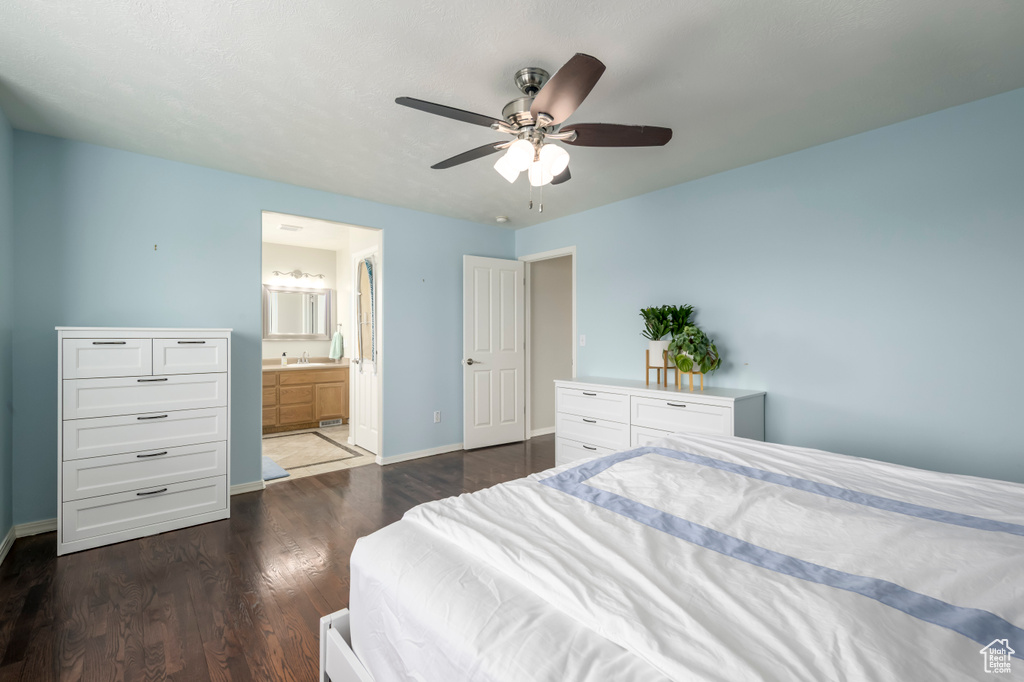 Bedroom with dark wood-type flooring, baseboards, a ceiling fan, and connected bathroom