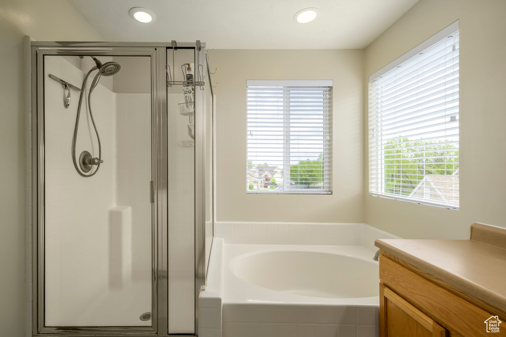 Full bathroom with a stall shower, a garden tub, vanity, and recessed lighting