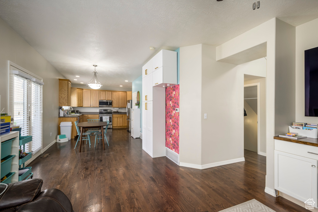 Kitchen featuring appliances with stainless steel finishes, recessed lighting, dark wood-type flooring, baseboards, and dark countertops