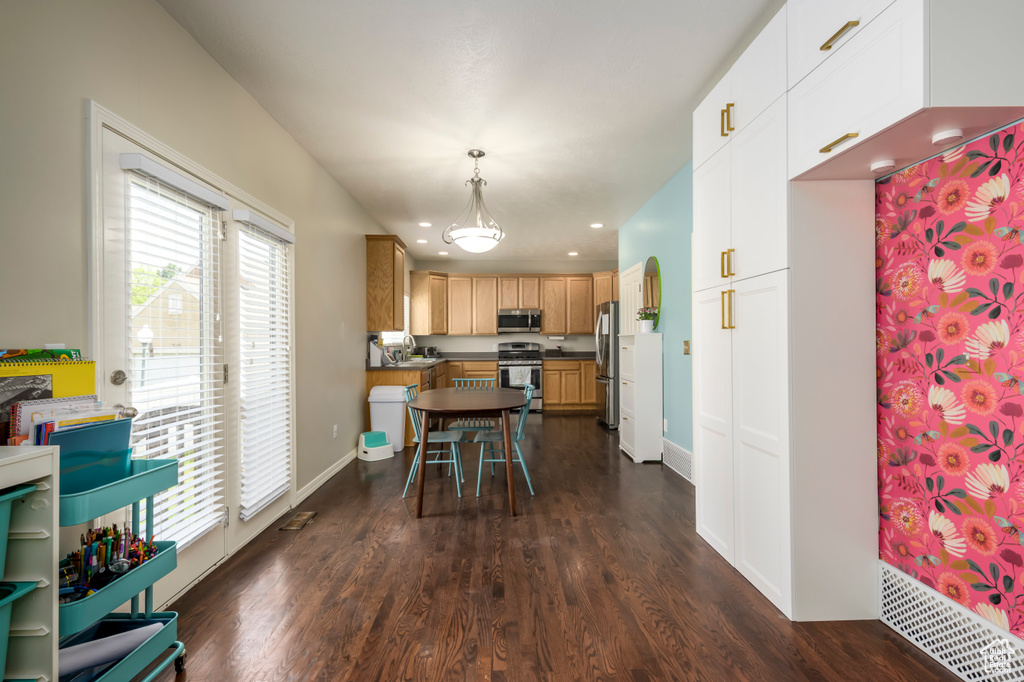 Kitchen with appliances with stainless steel finishes, dark countertops, dark wood-style floors, recessed lighting, and decorative light fixtures