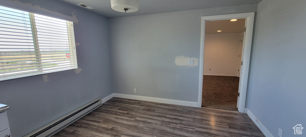Unfurnished room featuring baseboard heating, dark wood-type flooring, baseboards, and recessed lighting