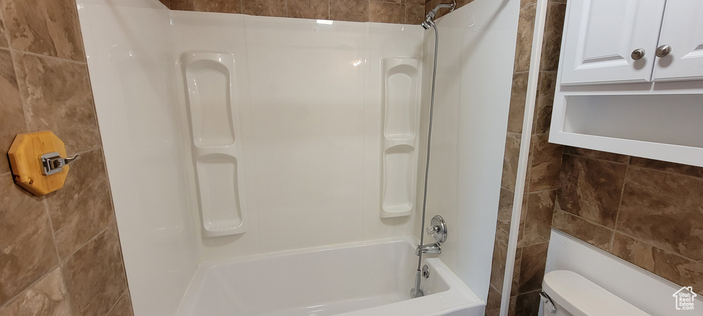 Bathroom with tile walls, toilet, and tub / shower combination