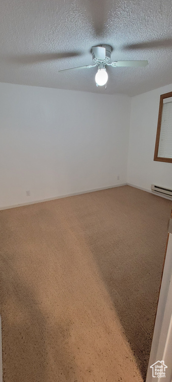 Spare room featuring light colored carpet, baseboard heating, a ceiling fan, and a textured ceiling