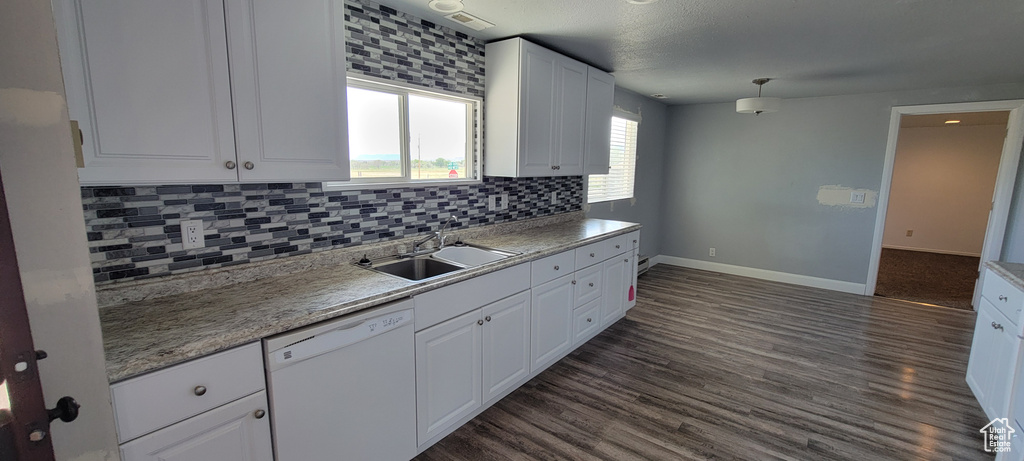 Kitchen featuring dishwasher, a sink, white cabinets, baseboards, and decorative backsplash
