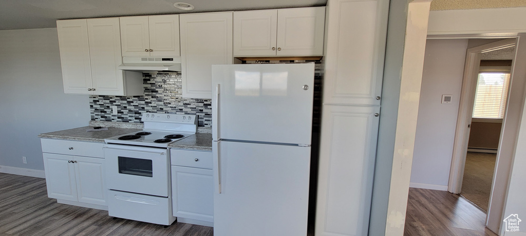 Kitchen with white appliances, under cabinet range hood, light wood-style floors, tasteful backsplash, and white cabinetry