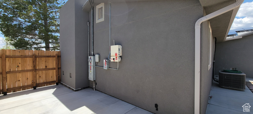 View of side of home with stucco siding, cooling unit, and fence