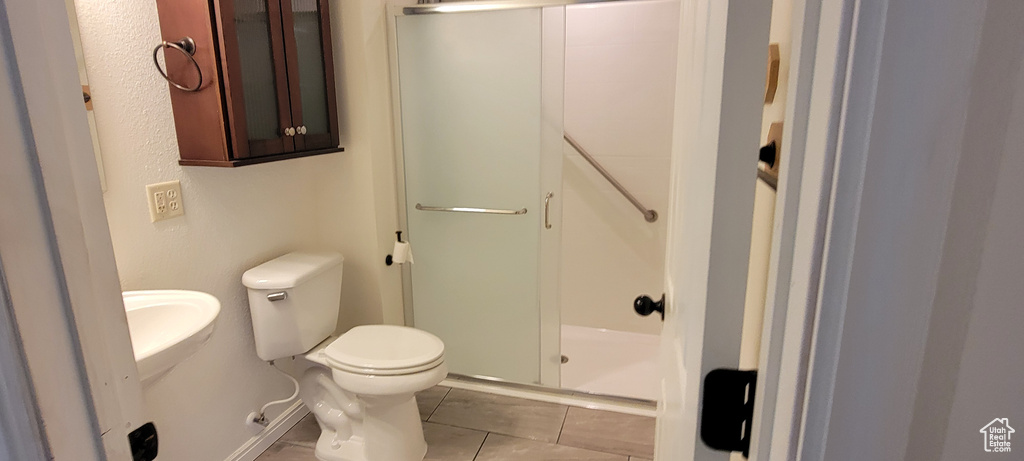 Bathroom featuring a stall shower, toilet, and tile patterned flooring