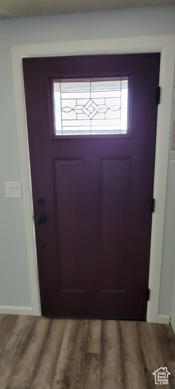 Doorway to outside featuring wood finished floors, plenty of natural light, and baseboards