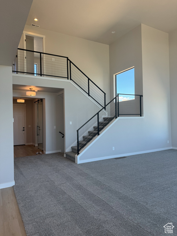 Stairway featuring baseboards, a high ceiling, recessed lighting, carpet floors, and wood finished floors