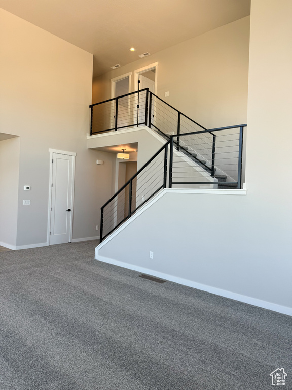 Stairway with carpet floors, a high ceiling, and baseboards