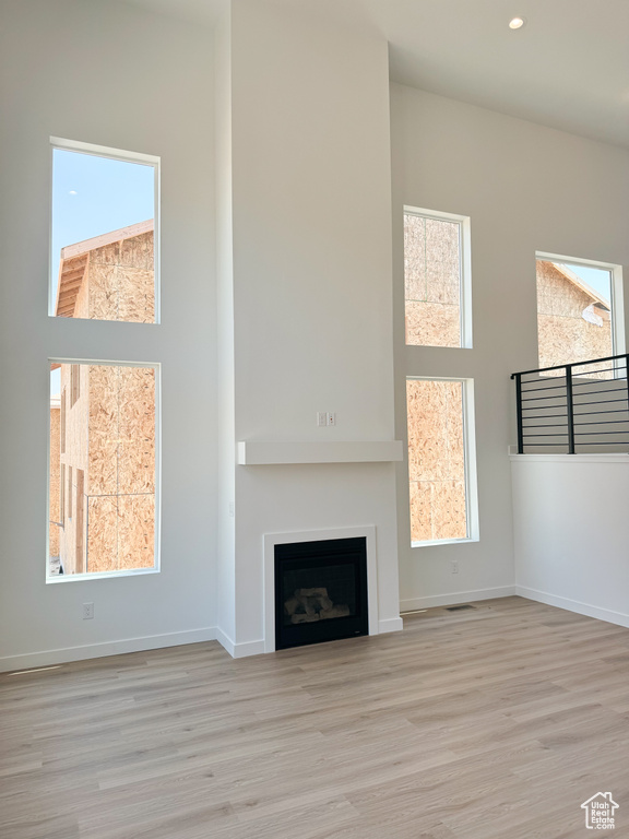 Unfurnished living room with wood finished floors, healthy amount of natural light, a fireplace, and recessed lighting