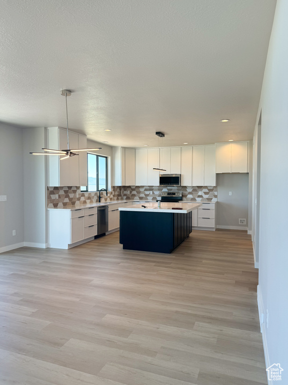 Kitchen featuring appliances with stainless steel finishes, backsplash, white cabinets, recessed lighting, and a textured ceiling