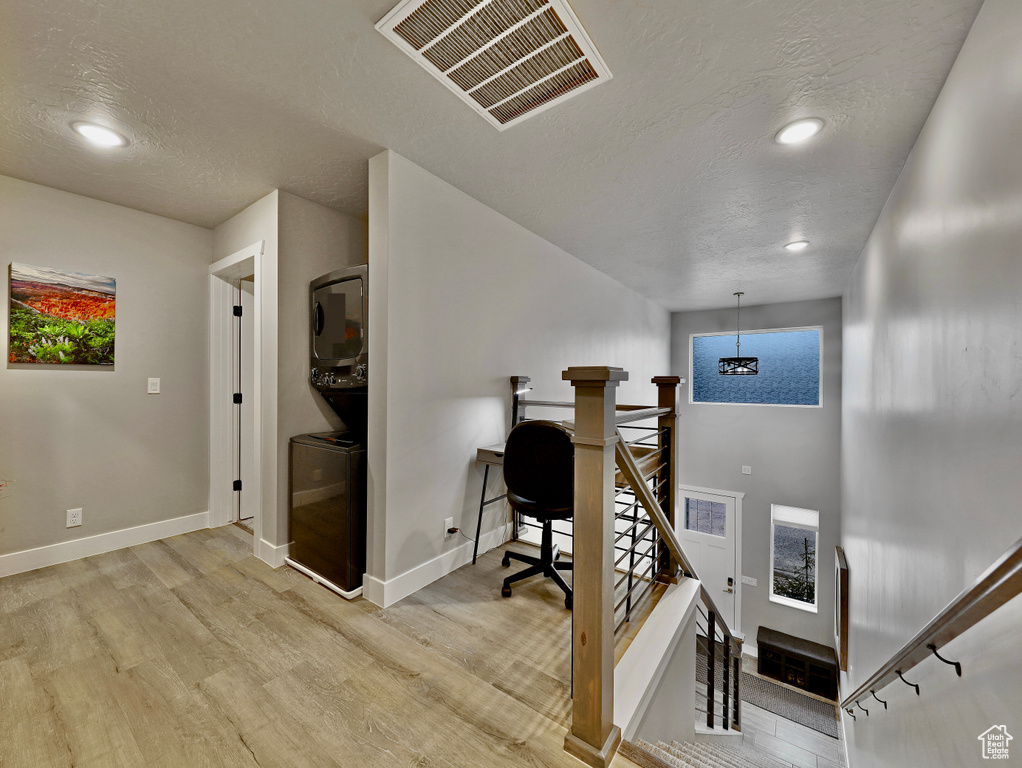 Office featuring estacked washer and dryer, a textured ceiling, light wood-style floors, baseboards, and recessed lighting