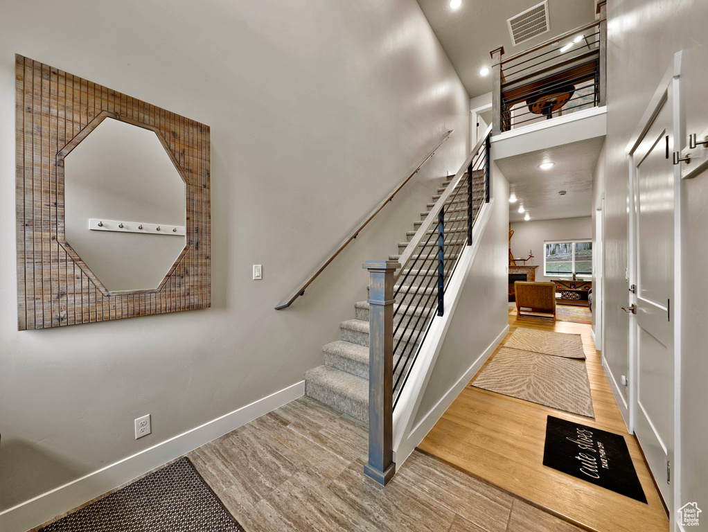 Stairs with baseboards, wood finished floors, a high ceiling, and recessed lighting