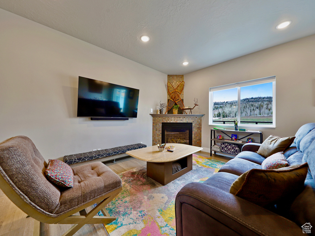 Living area with recessed lighting, wood finished floors, and a fireplace