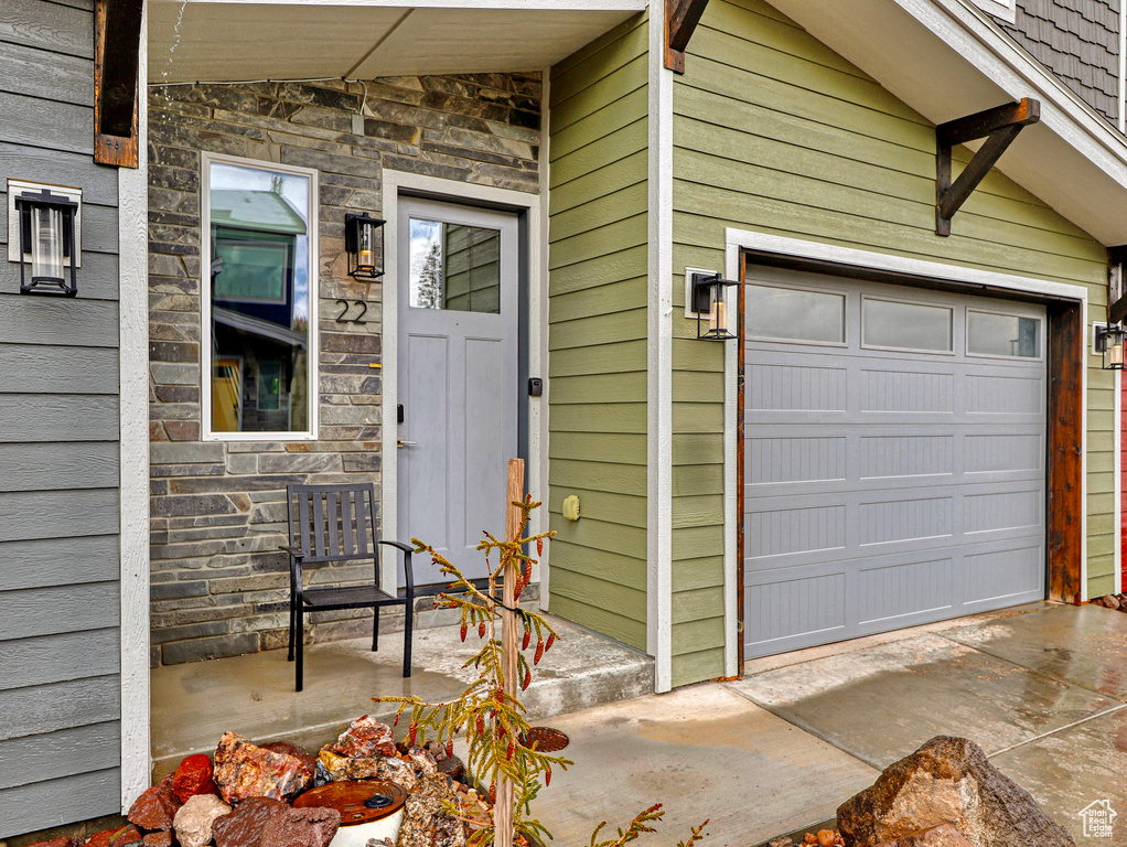 Property entrance with stone siding and a garage