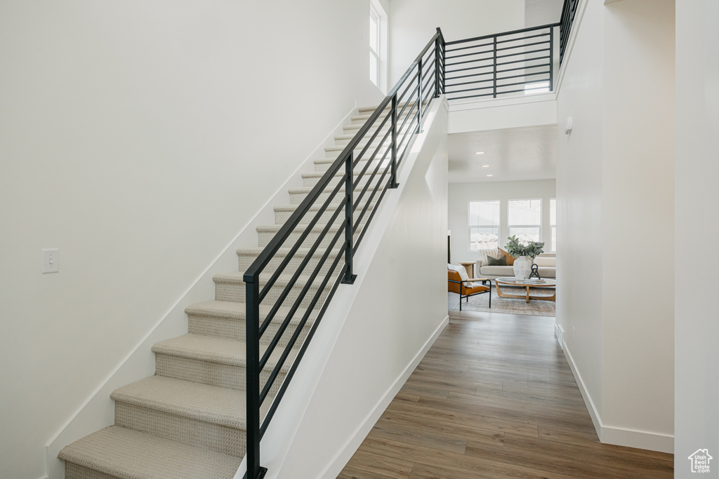 Stairway featuring wood finished floors, baseboards, and a towering ceiling