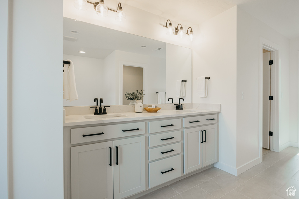 Bathroom with double vanity, tile patterned flooring, and baseboards