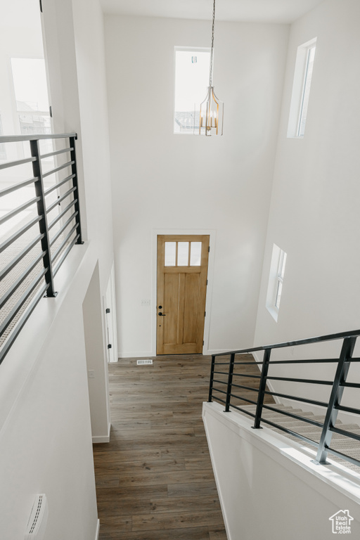 Entrance foyer featuring a towering ceiling, dark wood finished floors, a chandelier, and healthy amount of natural light