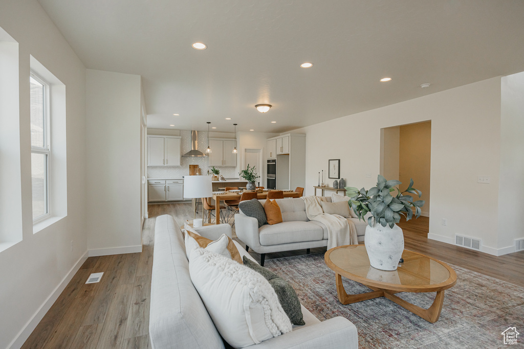 Living room with wood finished floors, baseboards, and recessed lighting