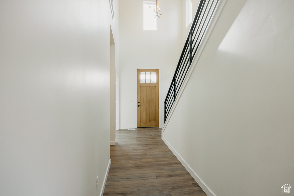 Corridor with stairs, baseboards, dark wood finished floors, a chandelier, and a high ceiling