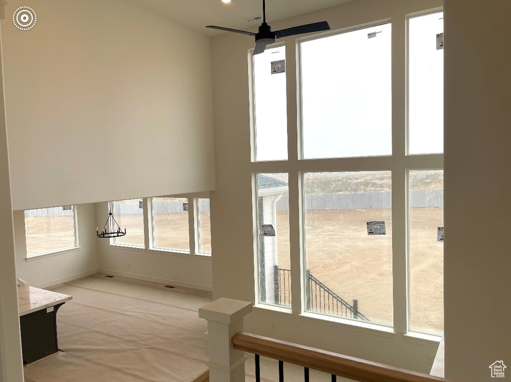 Unfurnished living room featuring ceiling fan, baseboards, and carpet floors
