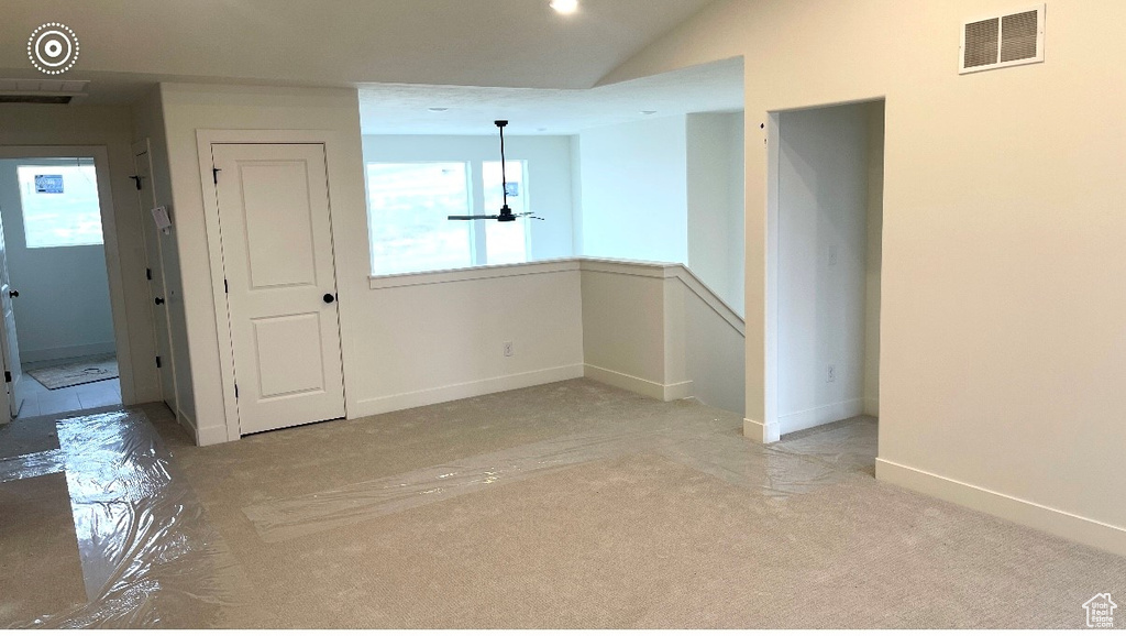 Empty room with carpet floors, lofted ceiling, and baseboards