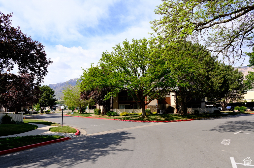View of asphalt road with a mountain view, sidewalks, and curbs