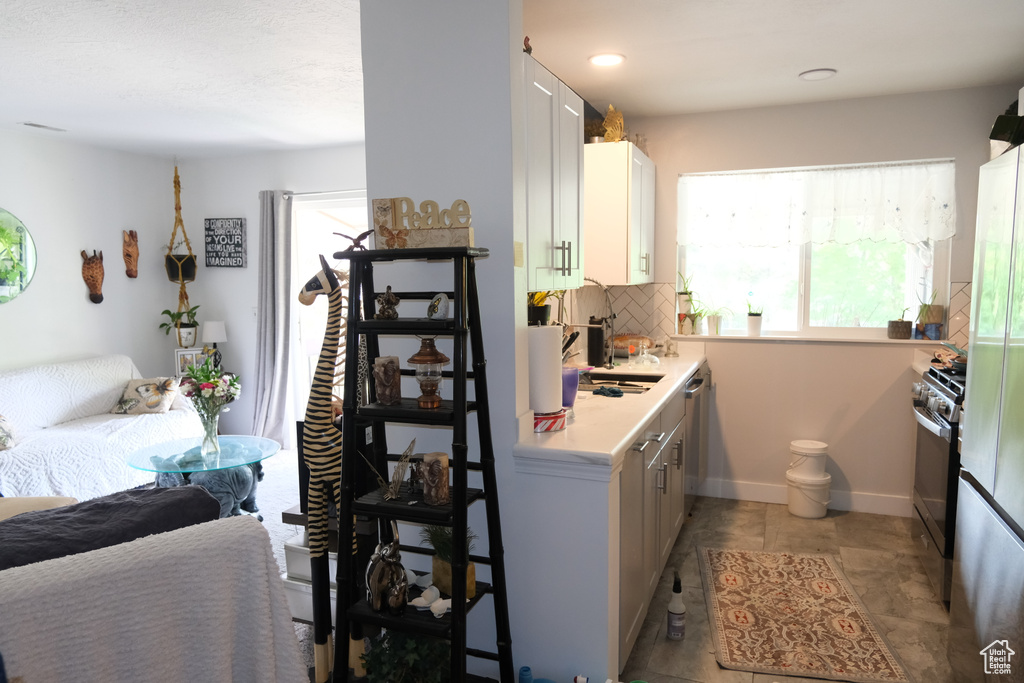 Kitchen with light countertops, decorative backsplash, healthy amount of natural light, and gas range