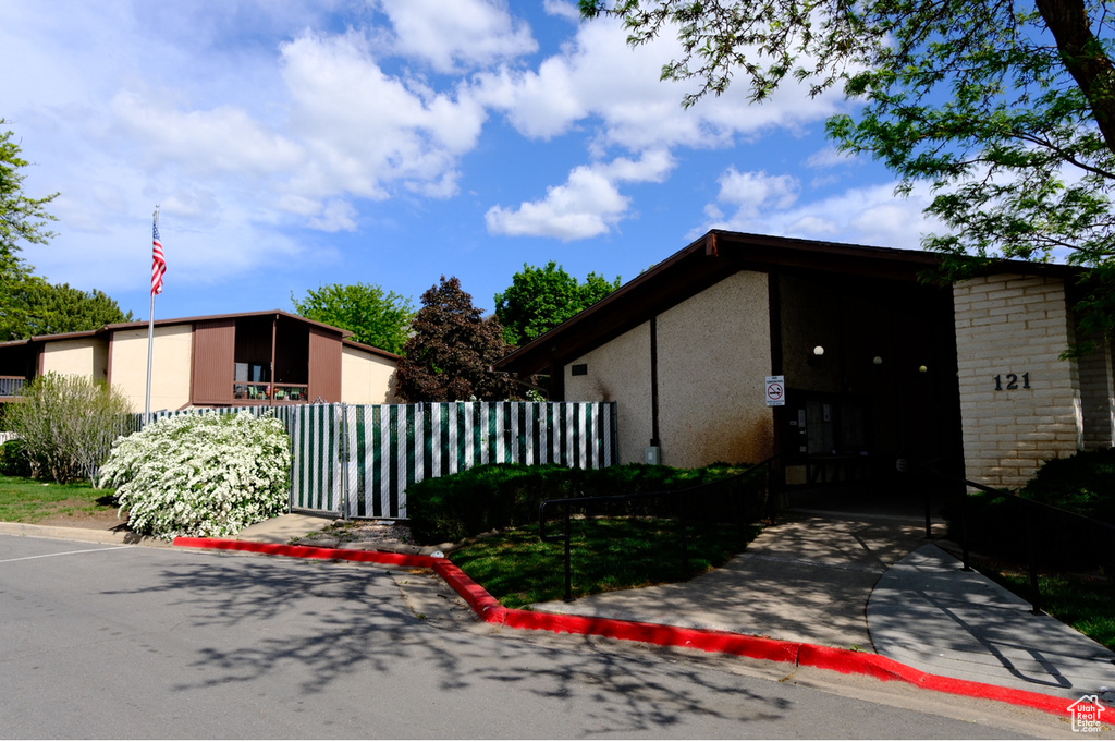 View of front of property featuring fence, stucco siding, and a gate