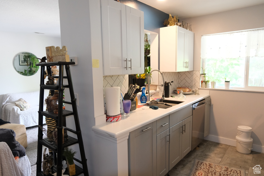 Kitchen with a sink, stainless steel dishwasher, backsplash, and light countertops