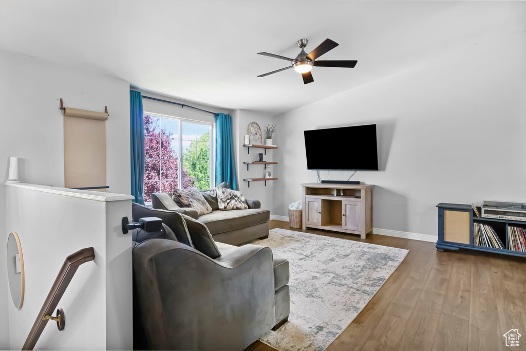 Living area with a ceiling fan, wood finished floors, and baseboards