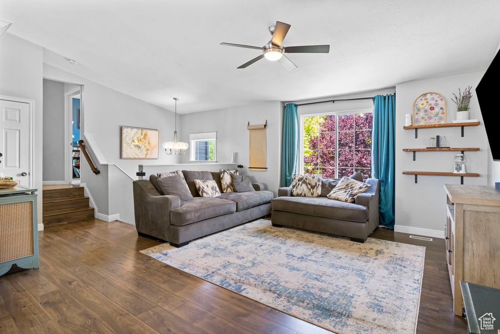 Living area featuring a ceiling fan, dark wood-style flooring, a chandelier, and plenty of natural light