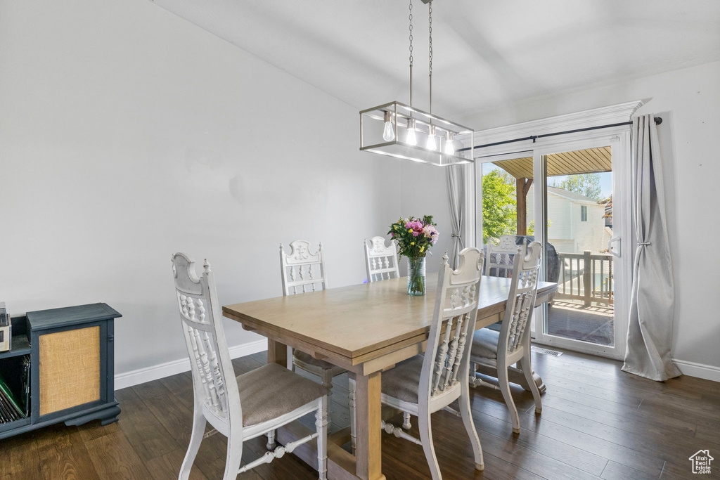 Dining area with baseboards, dark wood-type flooring, and a chandelier