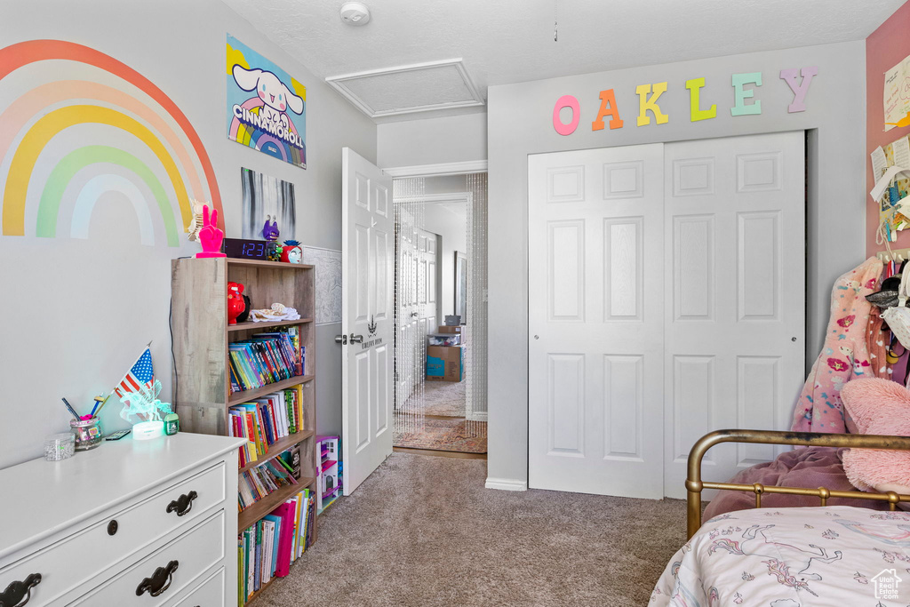 Bedroom with attic access, a closet, and carpet flooring