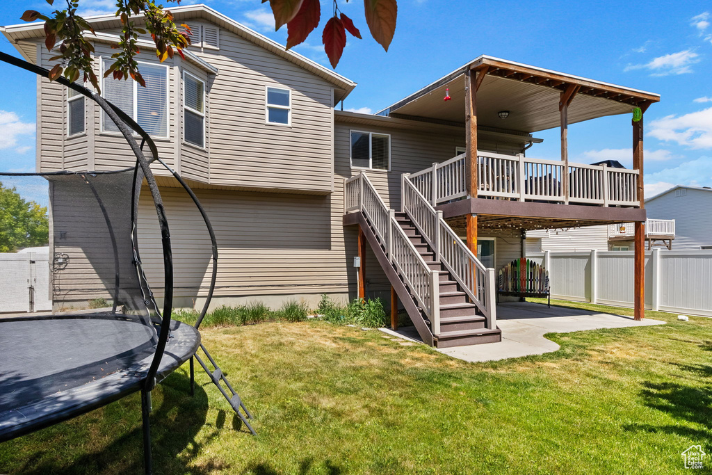 Rear view of house featuring a trampoline, a patio, a deck, and stairway