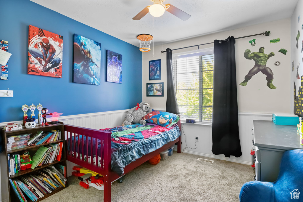 Bedroom featuring multiple windows, wainscoting, carpet flooring, and a ceiling fan