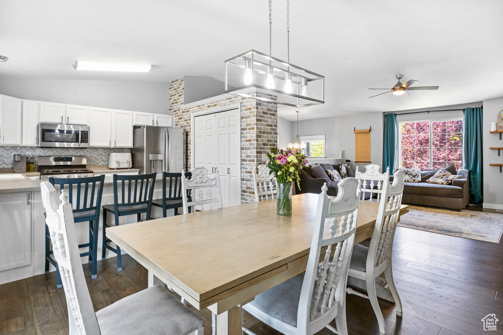 Dining area with vaulted ceiling, a ceiling fan, and dark wood-style floors