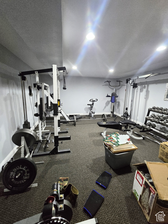 Gym featuring a textured ceiling and baseboards
