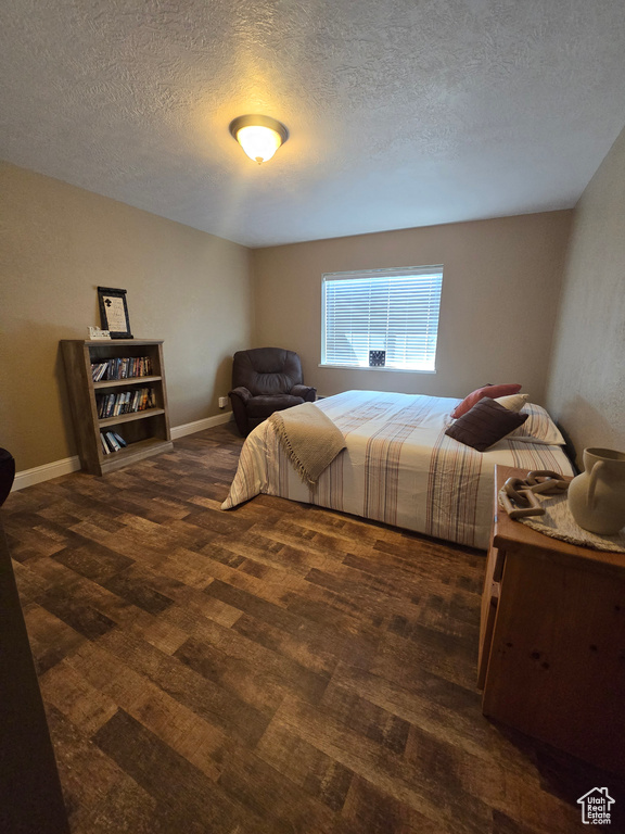 Bedroom with a textured ceiling, baseboards, and wood finished floors