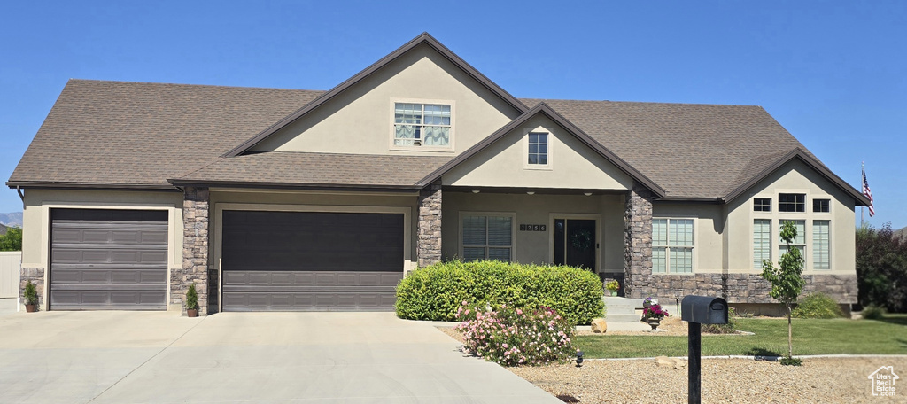 Craftsman-style home featuring stone siding, stucco siding, concrete driveway, an attached garage, and a shingled roof