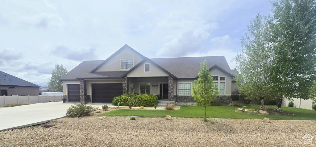 View of front of property with stone siding, driveway, a garage, and stucco siding